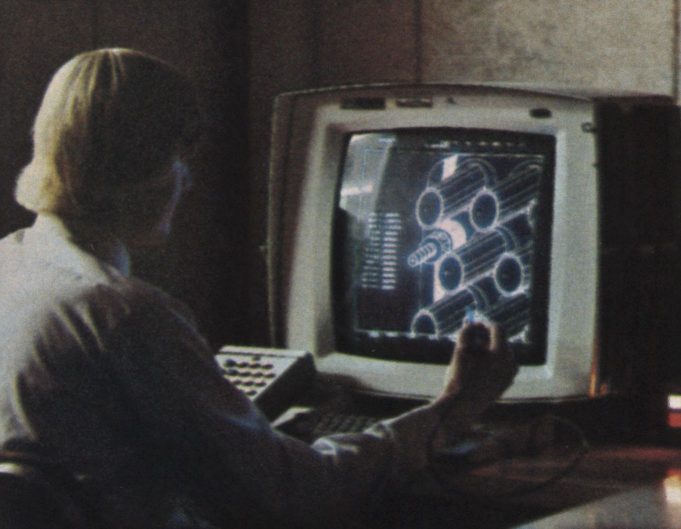 An engineer studies a detailed 3D model on a CAD workstation with dual monitors.